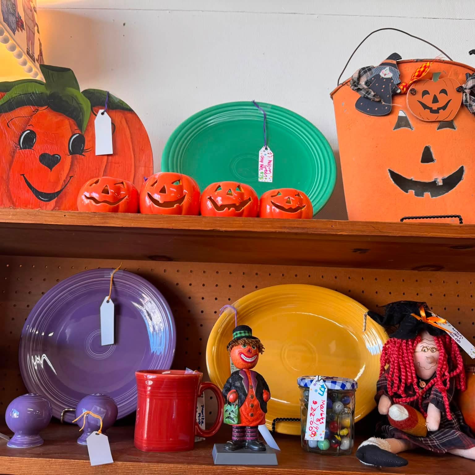 Ceramic jack-o-lanterns and brightly colored dinner plates on painted shelves