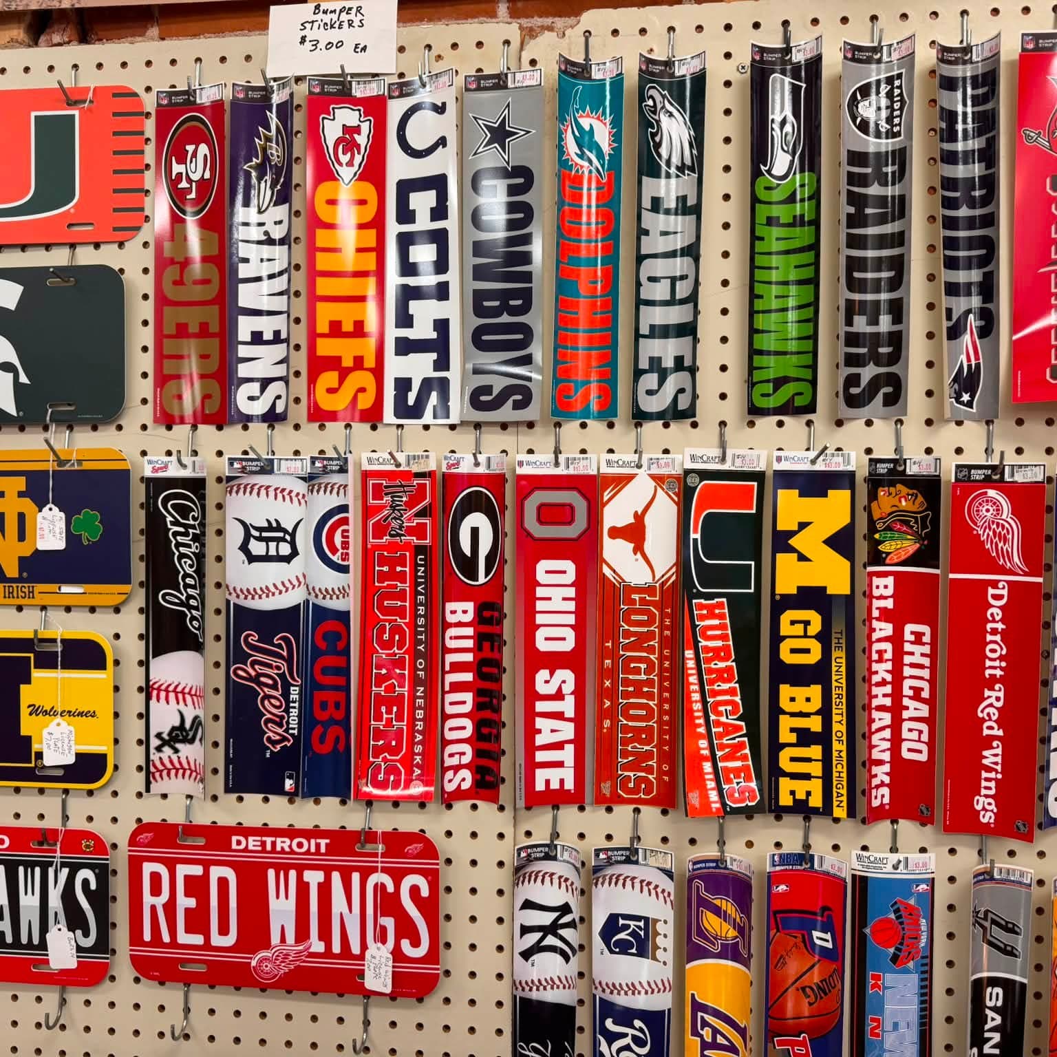Pegboard wall of NFL, college and Detroit Red Wings license plates and signs